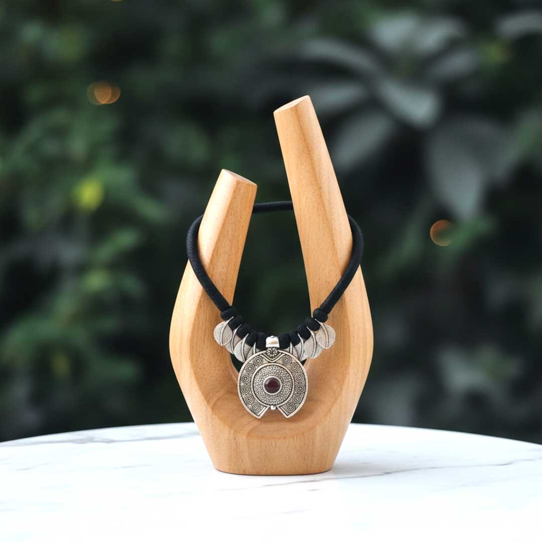 Necklace with a pendant on a wooden stand against a blurred green background