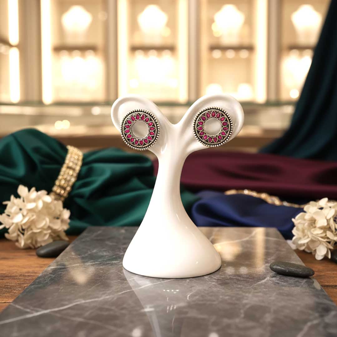 Pair of earrings on a white stand with a blurred background