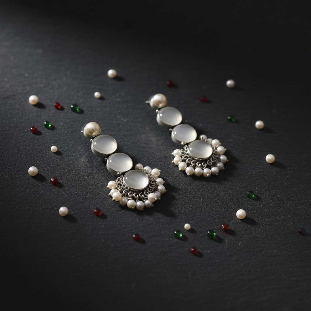 Pair of silver earrings with pearls on a dark surface