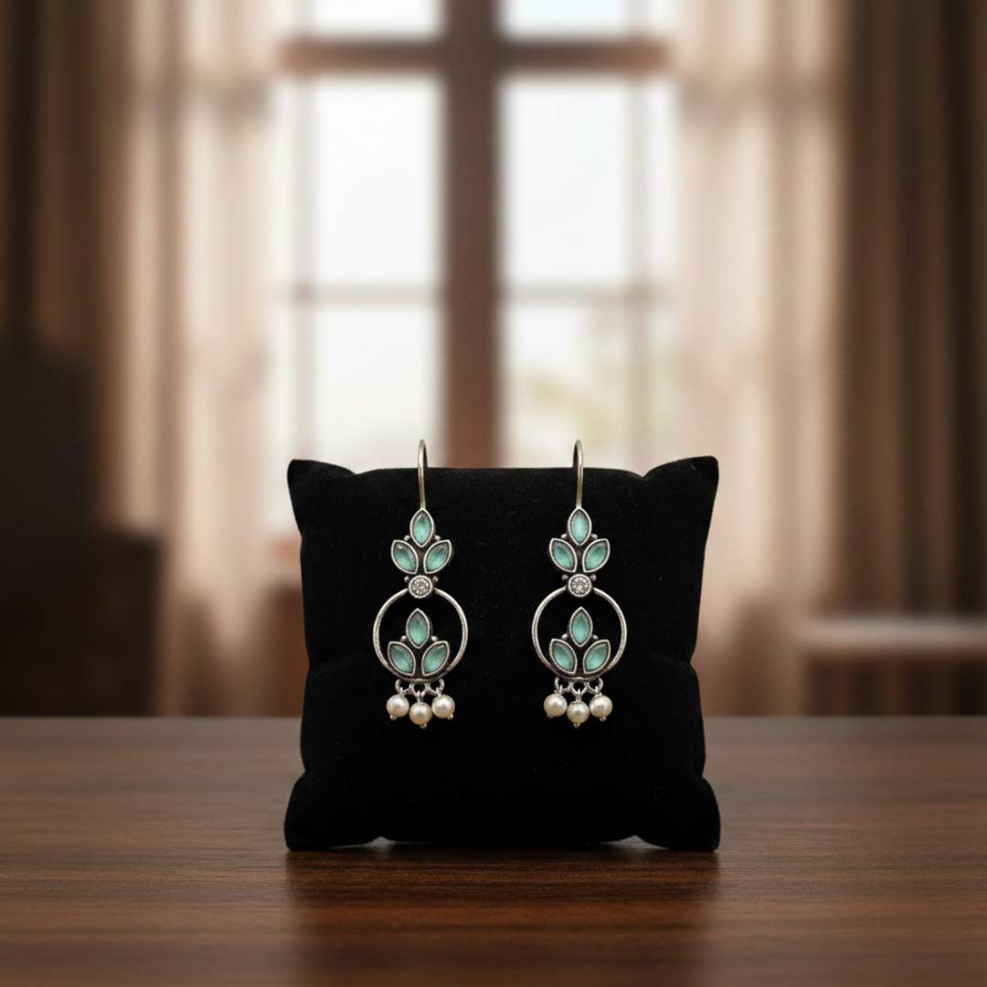 Pair of earrings on a black cushion with a blurred window background