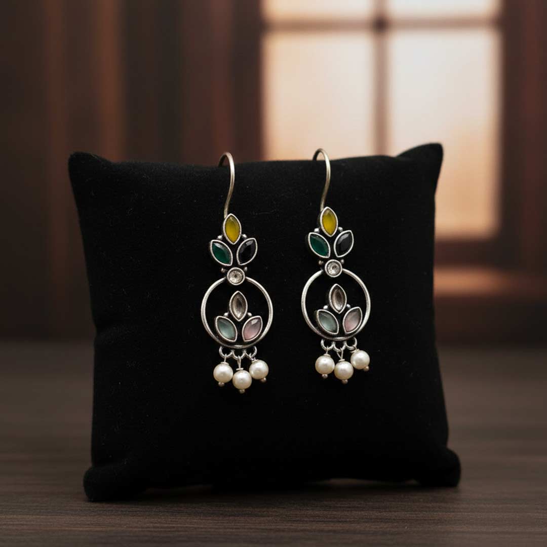 Pair of silver earrings with gemstones on a black cushion