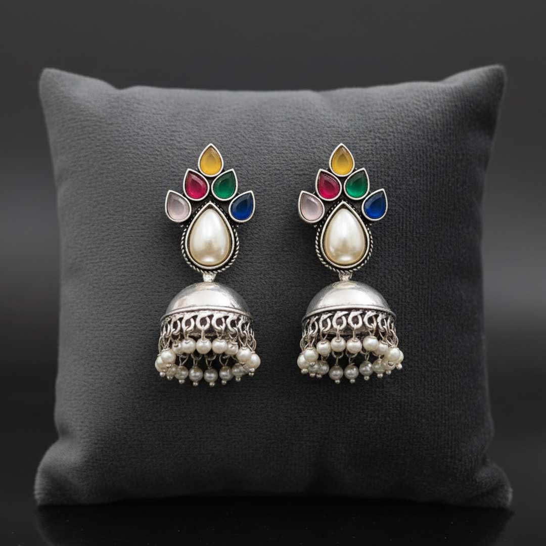 Pair of ornate earrings with colorful gemstones on a gray cushion
