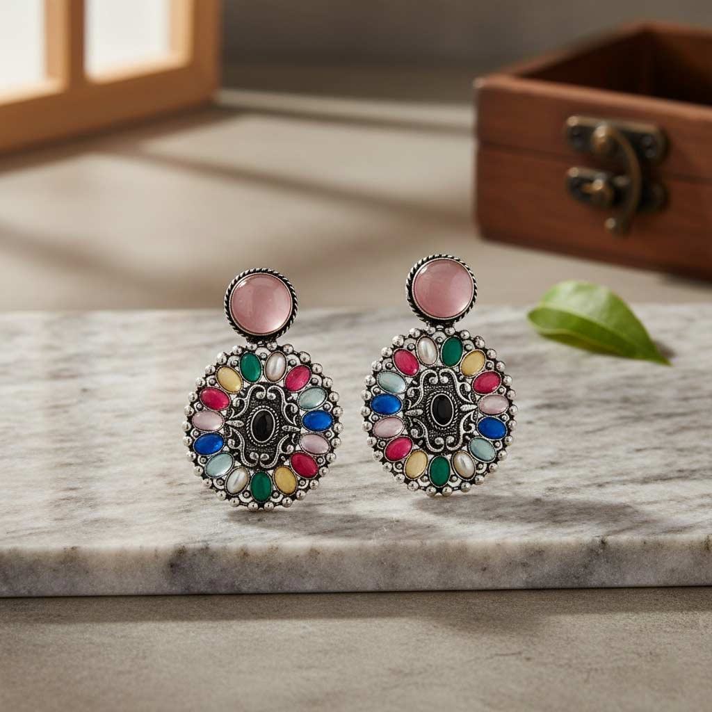 Colorful gemstone earrings on a marble surface with a wooden box in the background.