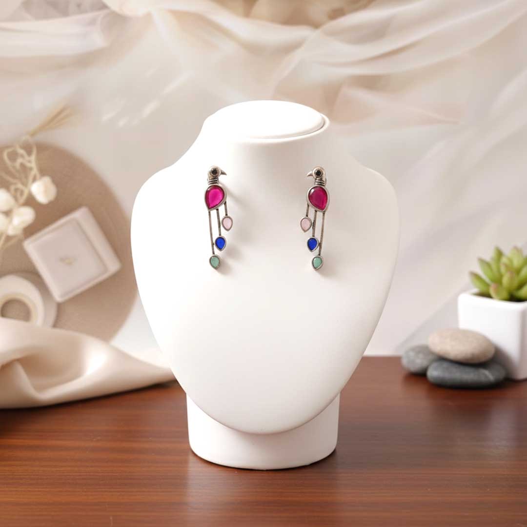 Pair of earrings on a white stand with a blurred background