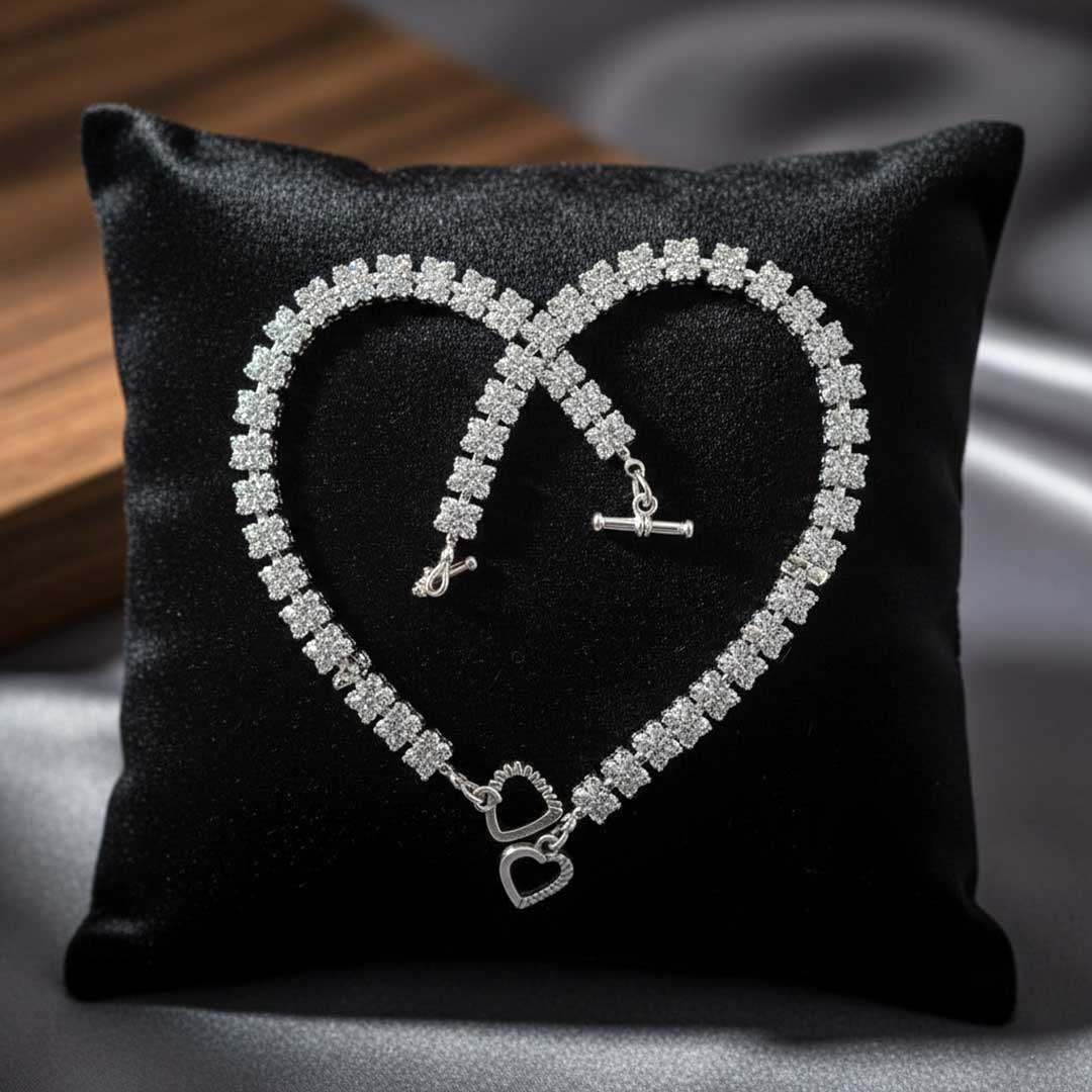 Silver bracelet shaped like an infinity symbol on a black pillow with a heart design.